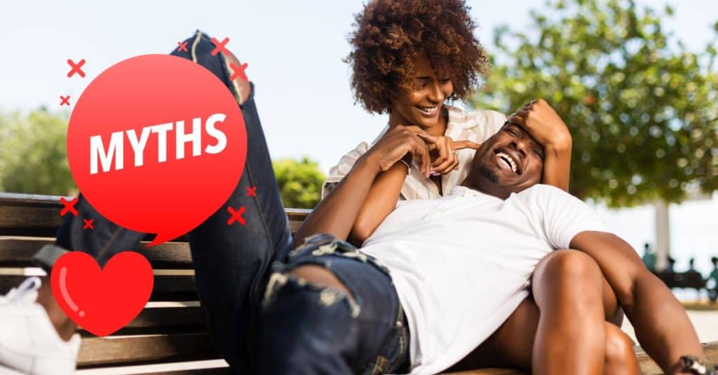 couple laughing together on bench with myth sign next to them