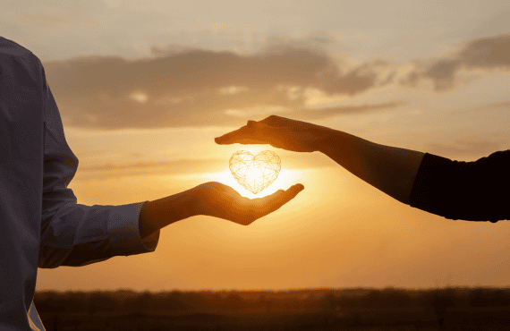 Concept of a Healthy Relationship - Two People at Sunset Holding a Heart