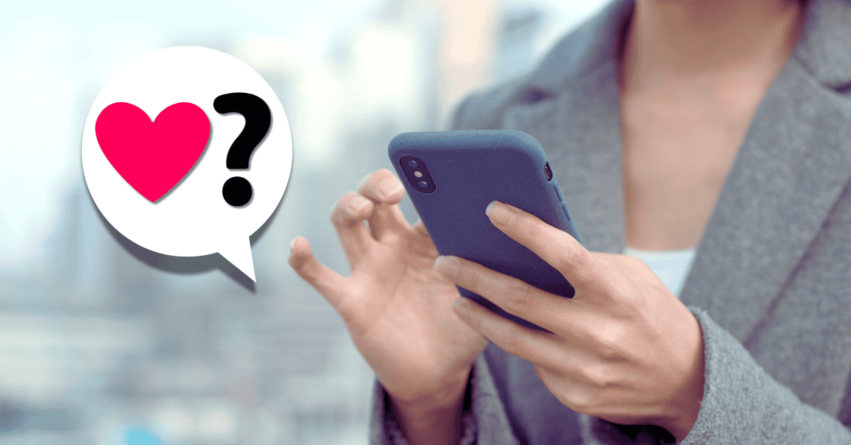 person holding smartphone in hand with speech bubble with heart and question mark