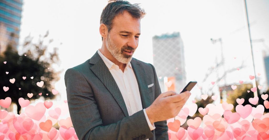 middle aged man smiling at phone with hearts in background